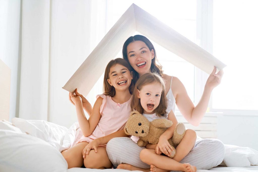 Mom and two daughters insured in OTP Insurance hold the roof symbol