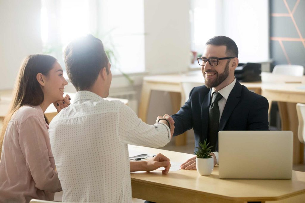 Smiling OTP Insurance worker shakes hands with a couple